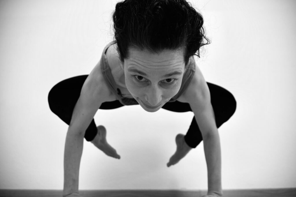 schwarz weiß foto einer Frau von vorne in Yoga Pose Krähe